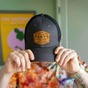 Person wearing a grey Tony's Badge Trucker Hat with leather patch