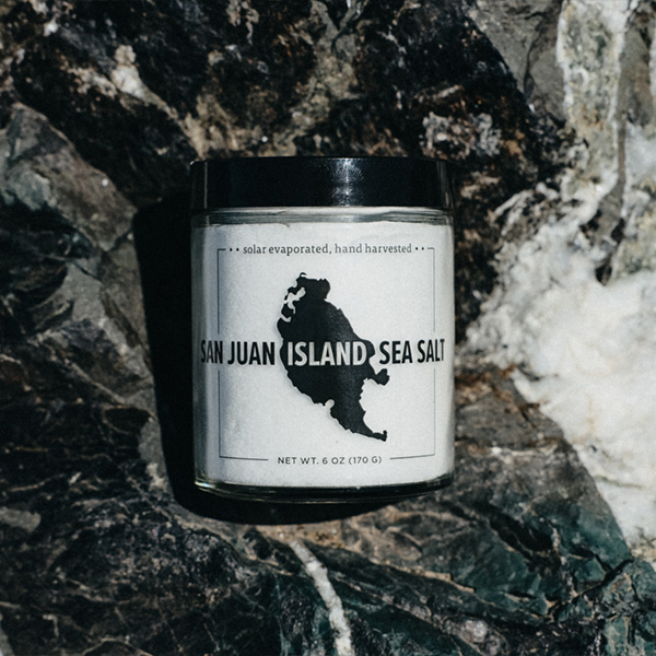 Jar of San Juan Island Sea Salt Natural Sea Salt sitting on a grey and white rock