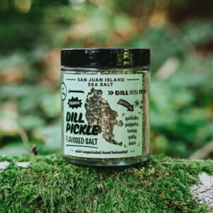 Jar of San Juan Island Sea Salt Dill Pickle spice blend sitting on top of a mossy log