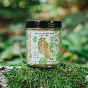 Jar of San Juan Island Sea Salt Spicy Thai spice blend sitting on top of a mossy log